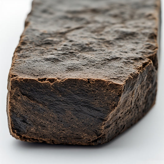 Close-up macro shot of THCA Moroccan hash showing the rich, crumbly texture and light golden trichome layer on a dark resin base.