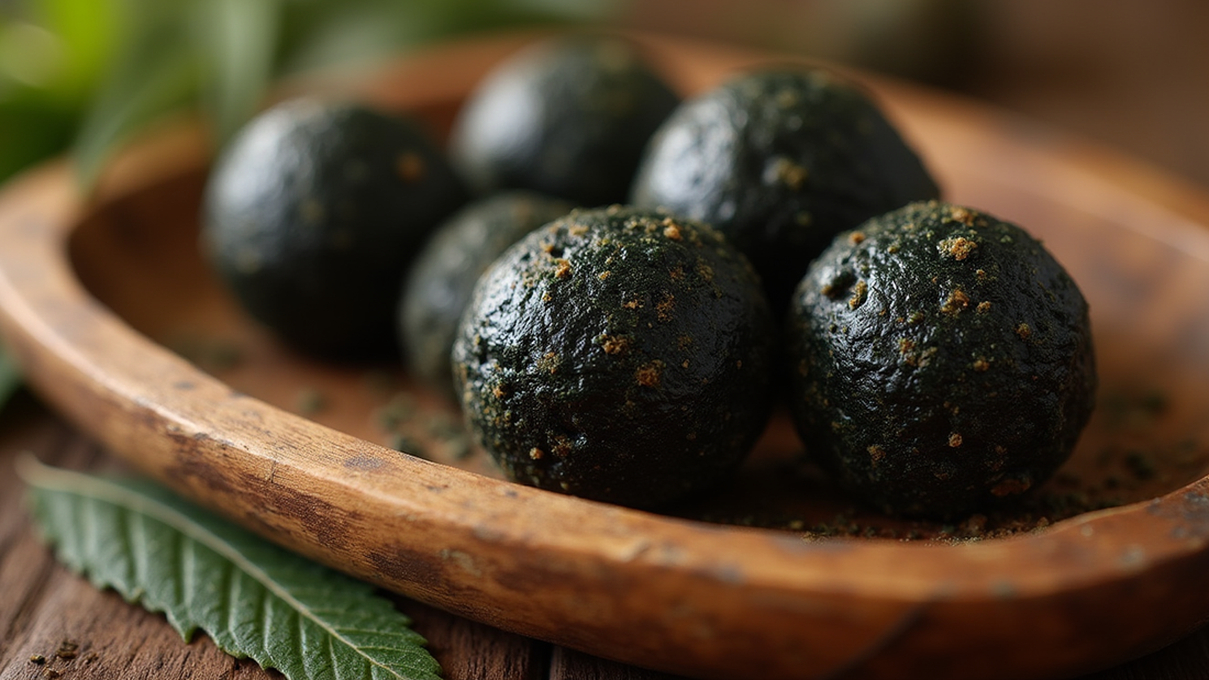 Close-up of traditional Afghan Temple Balls, dark, glossy, and resinous, placed on a rustic wooden tray with scattered hemp leaves