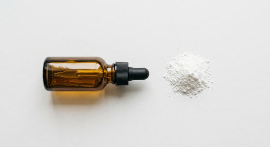 CBD isolate oil dropper bottle with pure white isolate powder on white surface