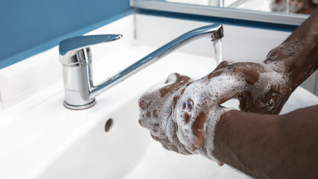 Hands lathering with CBD soap under a stream of water at a white sink with a chrome faucet. | Hurcann