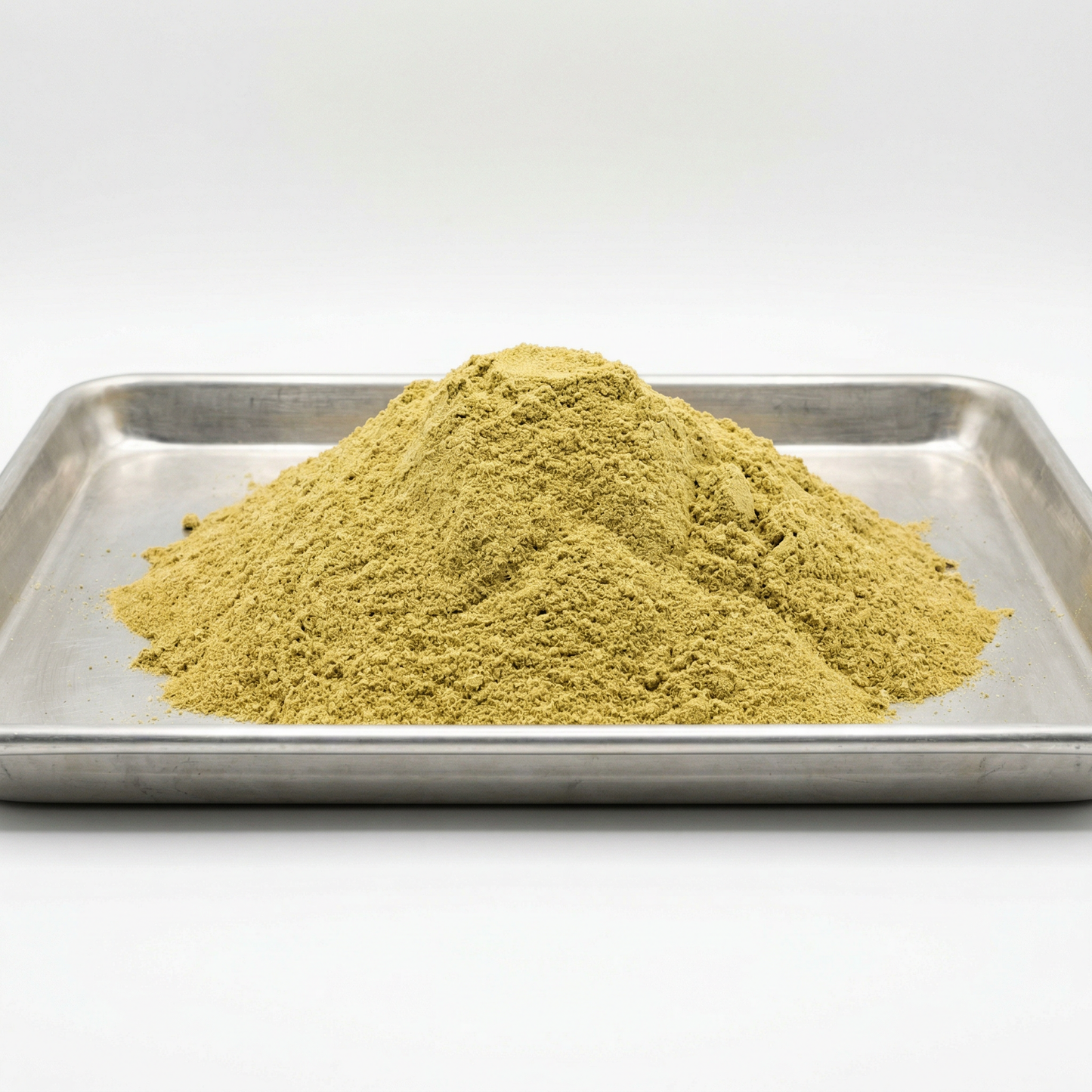 Bulk CBD kief powder mounded on a stainless steel tray — wholesale hemp-derived CBD kief, white background