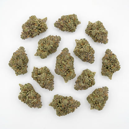 Top-down studio layout of multiple Gelato CBD flower buds arranged on a clean white background. The buds display dense structure with green tones, amber pistils, and visible trichome coverage throughout.