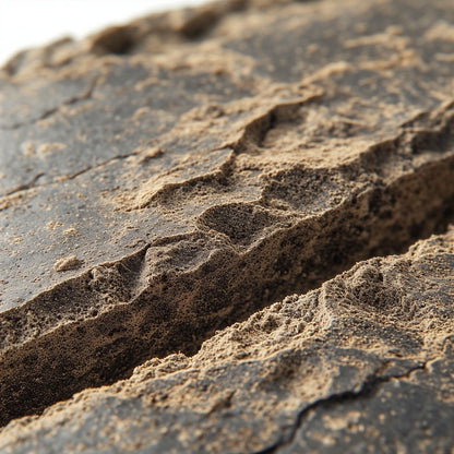 Dense, rectangular brick of Moroccan-style THCA hash with a dark, hand-pressed exterior and slightly porous interior texture